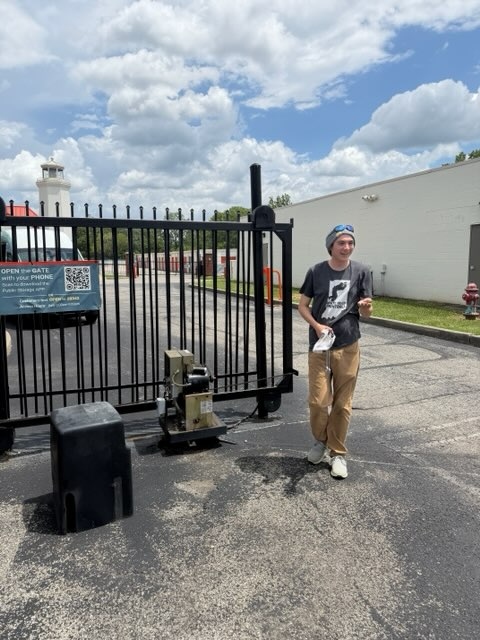 Technician assessing gate after trailer impact at storage facility