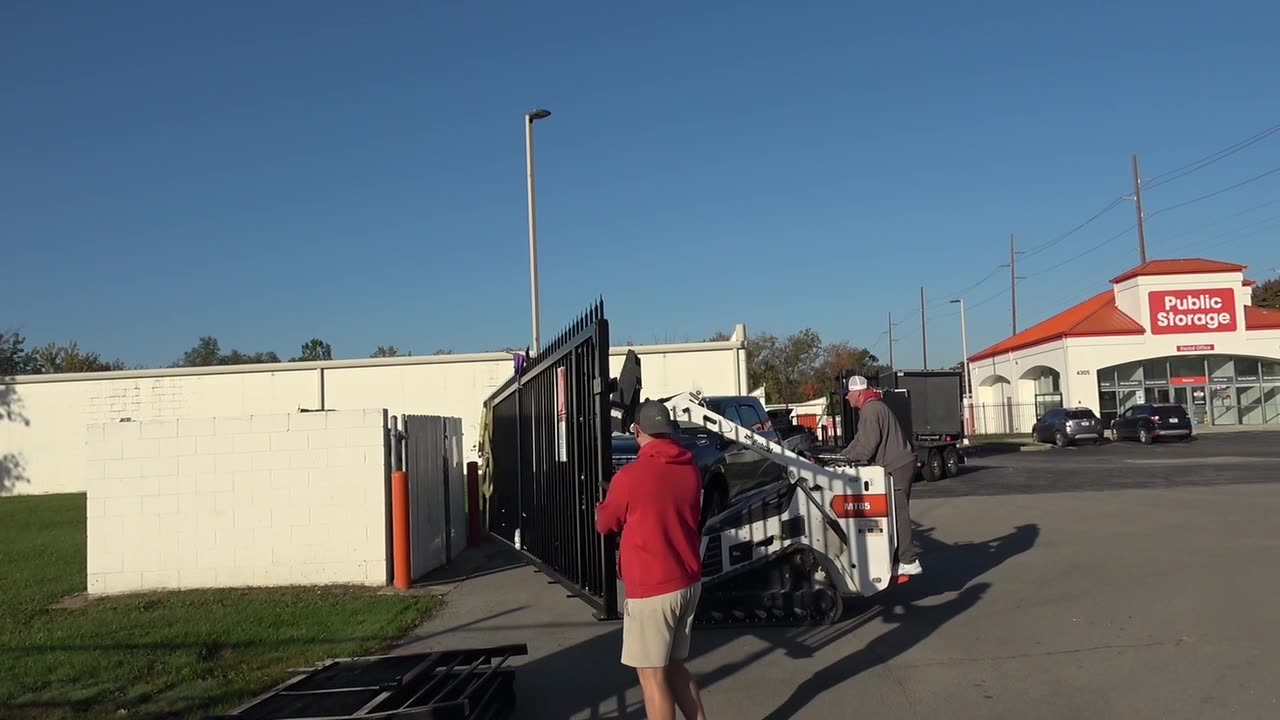 Bobcat setting a gate panel at a storage facility entry